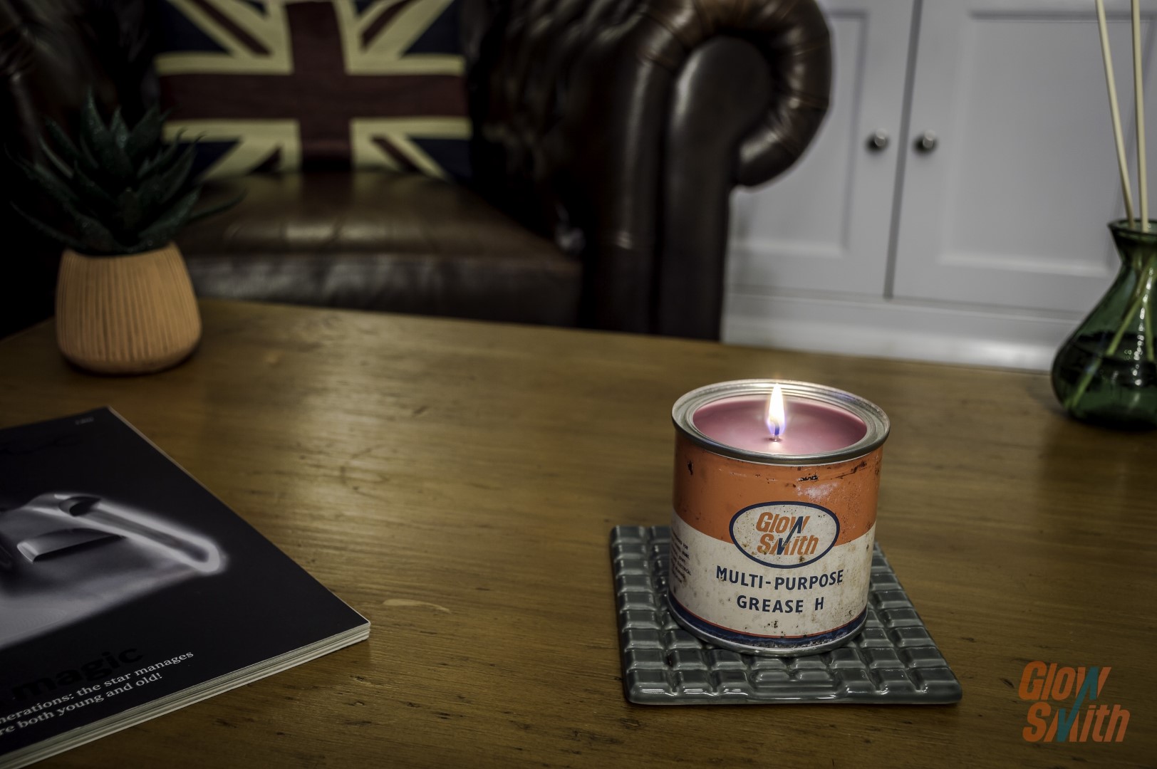 Lit Small Grease Tin Candle with Wild Pomegranate scent, casting a warm glow, perfect for vintage home decor.