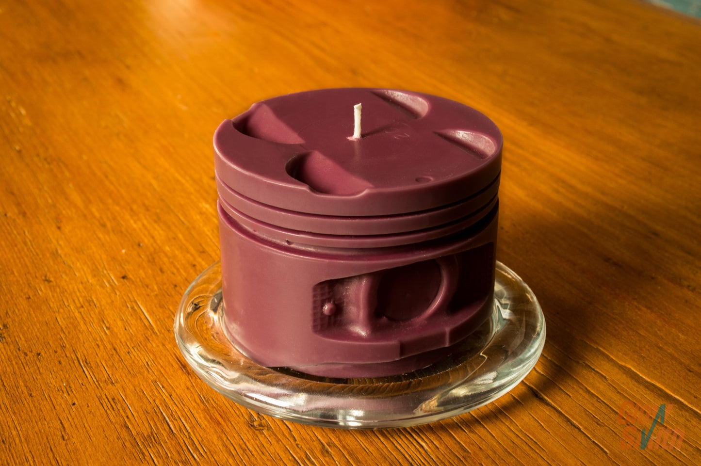 Close-up of maroon engine piston candle showing wax texture and shape