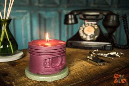 Maroon engine piston candle burning beside car memorabilia